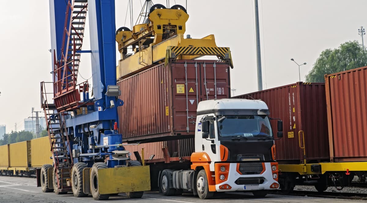 ein Container wird vom Lkw auf einer Güterzug geladen